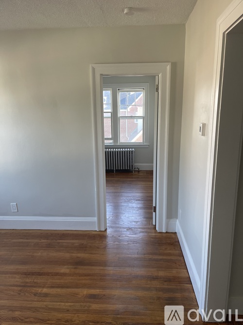A room with wooden floors and a window with a view of a building outside.