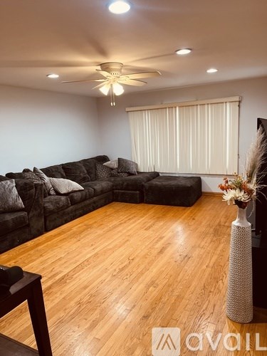 A living room with a dark grey sofa and wooden flooring.