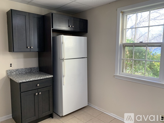 A kitchen with black cabinets and a white refrigerator.
