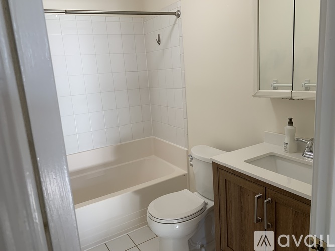 A white tiled bathroom with a toilet, sink, and bathtub.