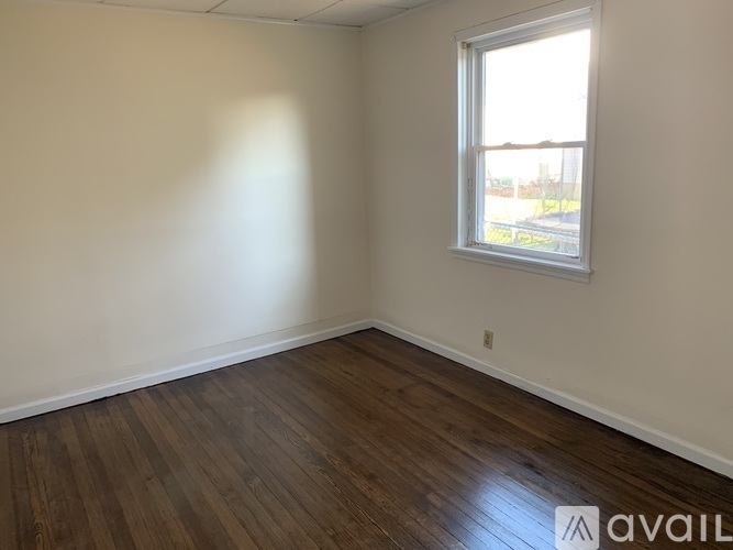 A room with wooden flooring and a window letting in natural light.