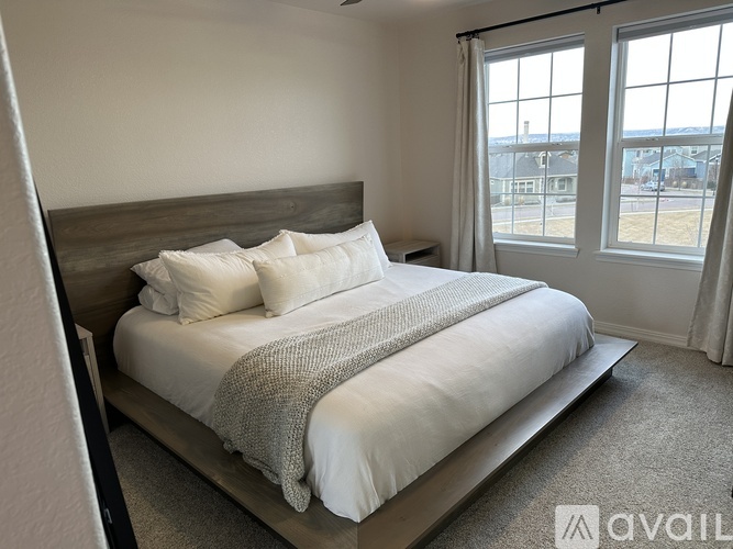 A bedroom with a large bed and a view of the outside through the window.