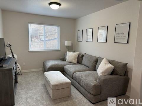 A living room with a grey couch and a white ottoman.