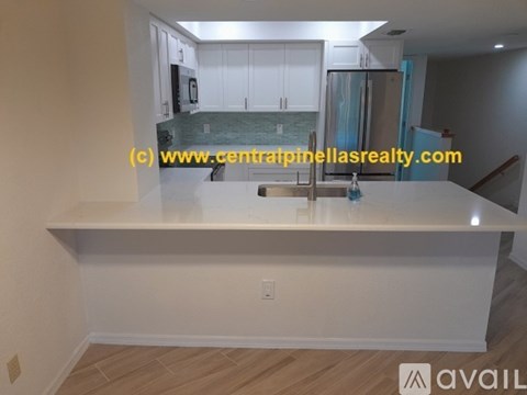 A kitchen with white cabinets and a countertop is available for rent.