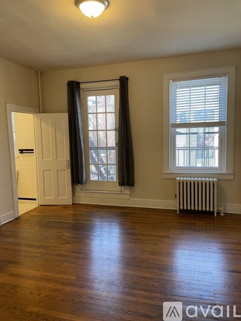 A room with wooden floors and a window with black curtains.
