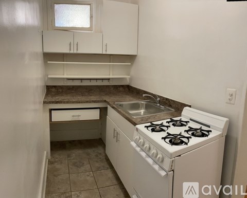 A kitchen with a white stove and white cabinets.