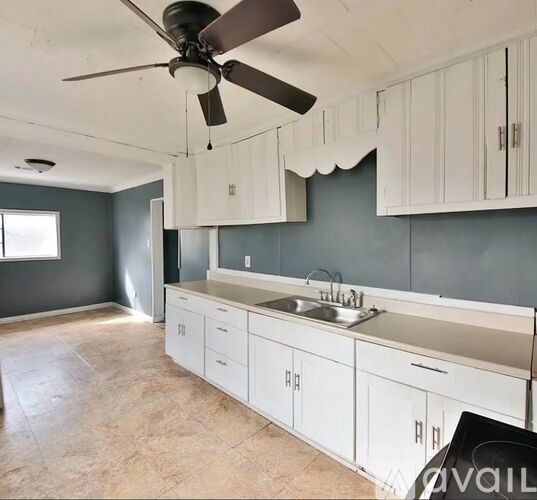A kitchen with white cabinets and a fan.