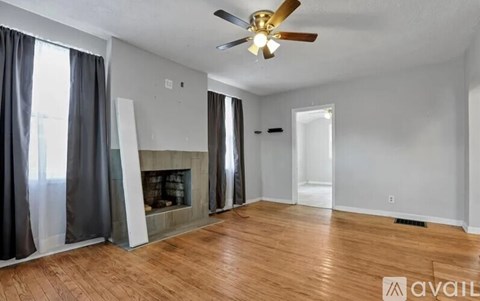 A living room with a fireplace and a ceiling fan.