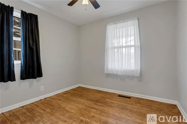 A room with a ceiling fan and a window with white curtains.