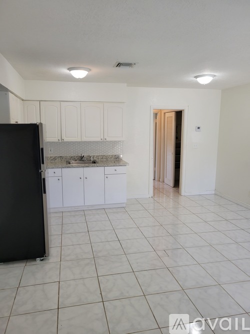 A kitchen with white cabinets and a black refrigerator.