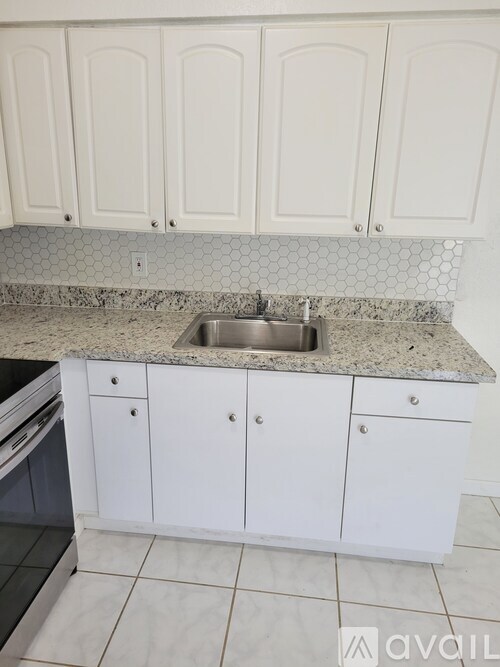 A kitchen with white cabinets and a granite countertop.