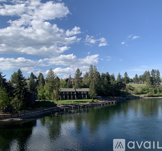 A serene lake with a dock and a building in the distance under a clear sky.