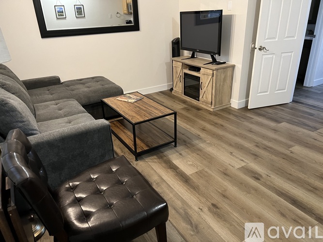 A living room with a grey couch, a black leather chair, and a wooden coffee table.