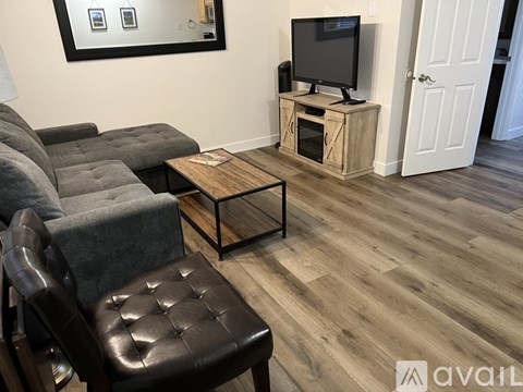 A living room with a grey couch, a black leather chair, and a wooden coffee table.