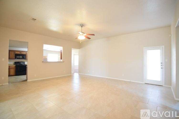 A spacious room with a ceiling fan and light, and a door leading to another room.