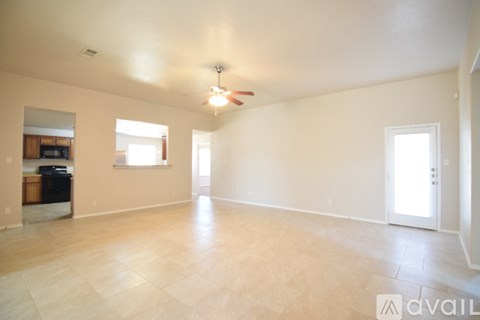 A spacious room with a ceiling fan and light, and a door leading to another room.