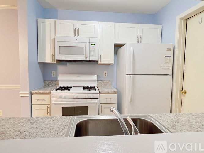 A kitchen with a white refrigerator, white stove, and white cabinets.