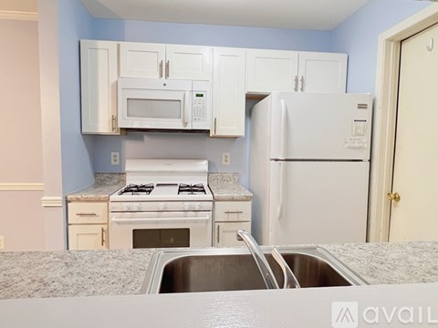 A kitchen with a white refrigerator, white stove, and white cabinets.