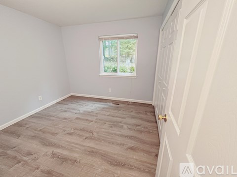 A room with a wooden floor and a window with a view of trees.