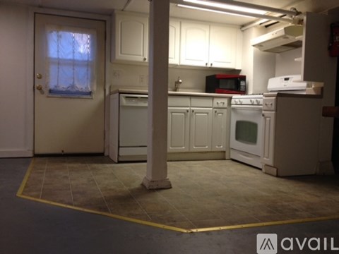 A kitchen with white cabinets and appliances, a window with curtains, and a yellow line on the floor.