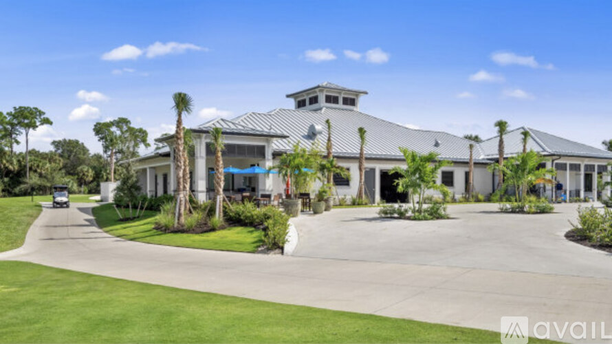 A large house with a driveway and palm trees in front.