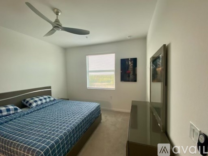 A bedroom with a bed, a ceiling fan, and a window with blinds.
