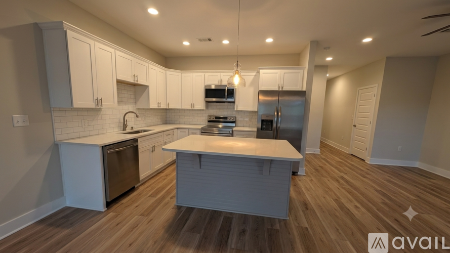 A modern kitchen with wooden floors and white cabinetry is available for rent.