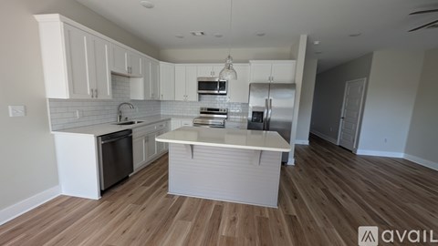 A kitchen with white cabinets and a wooden floor.