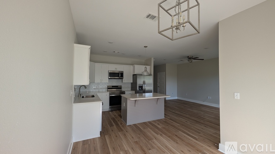 A modern kitchen with wooden floors and white cabinetry.