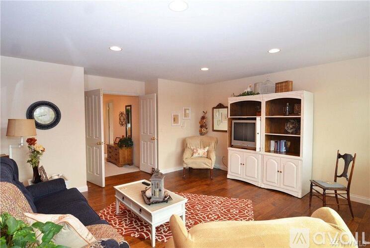 A living room with a white couch, a coffee table, and a television.