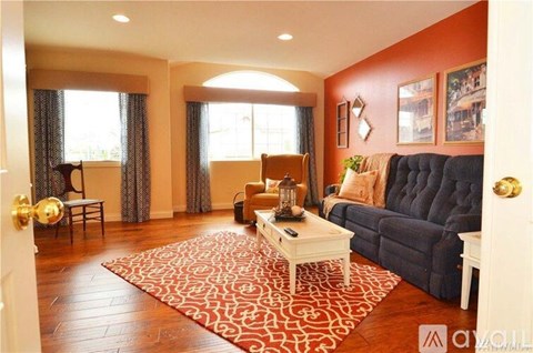 A living room with a blue couch and a red and white rug.