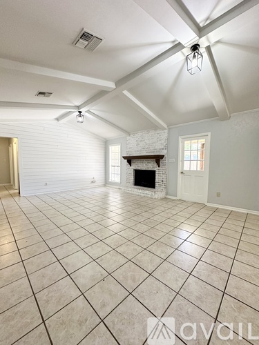 A spacious room with a fireplace and a tiled floor.