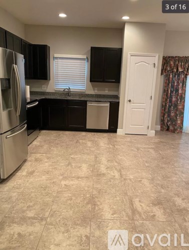 A kitchen with black cabinets and a stainless steel refrigerator.