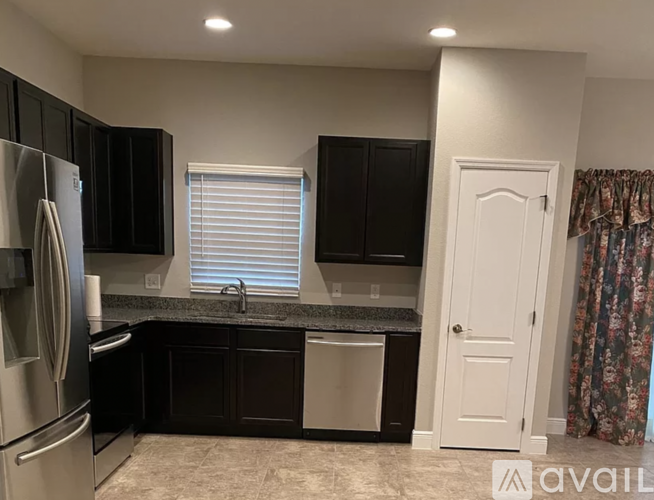 A kitchen with black cabinets and a stainless steel refrigerator.