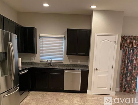 A kitchen with black cabinets and a stainless steel refrigerator.