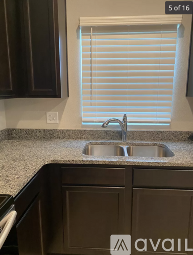 A kitchen with a sink and a window with blinds.