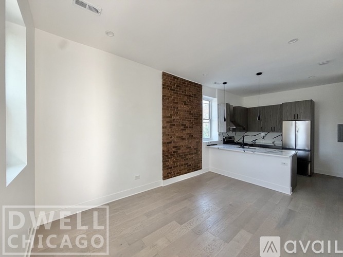 A spacious bedroom with a brick accent wall and a large bed.