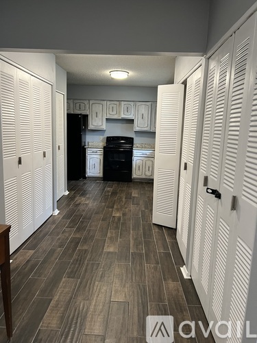 A kitchen with white cabinets and a wooden floor.