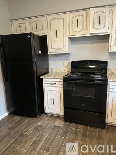 A black refrigerator and stove in a kitchen with wooden cabinets.