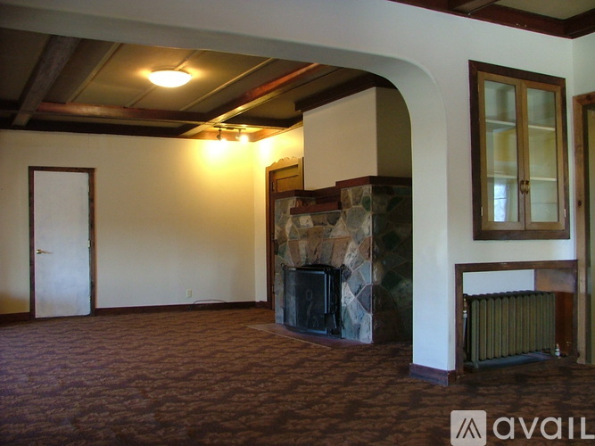 A room with a stone fireplace and a carpeted floor.