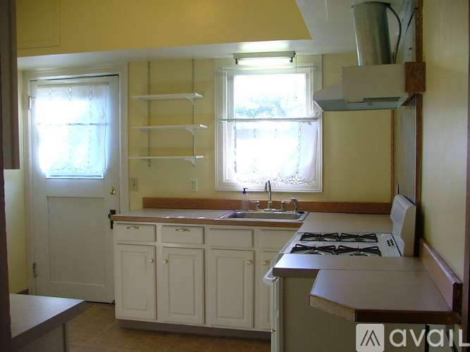 A kitchen with white cabinets and a window above the sink.