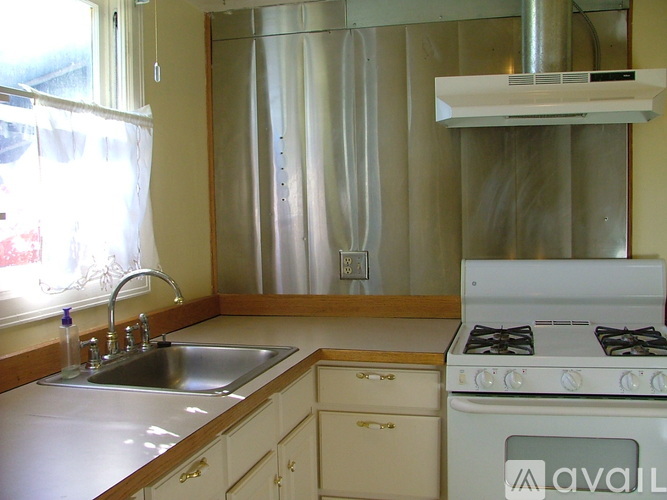 A kitchen with a stove, sink, and cabinets.