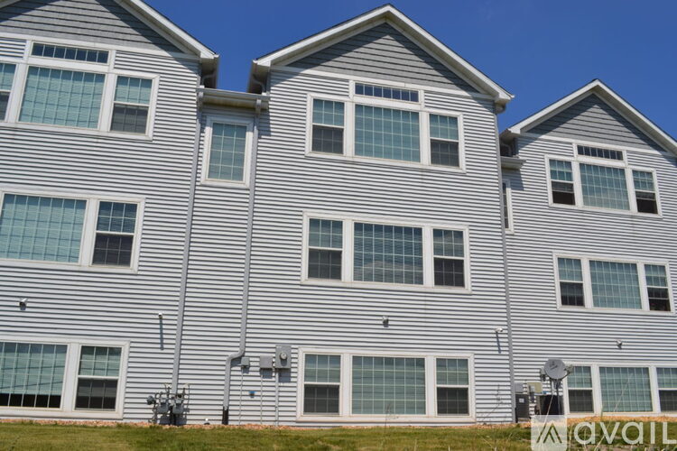 A grey building with multiple windows and satellite dishes.