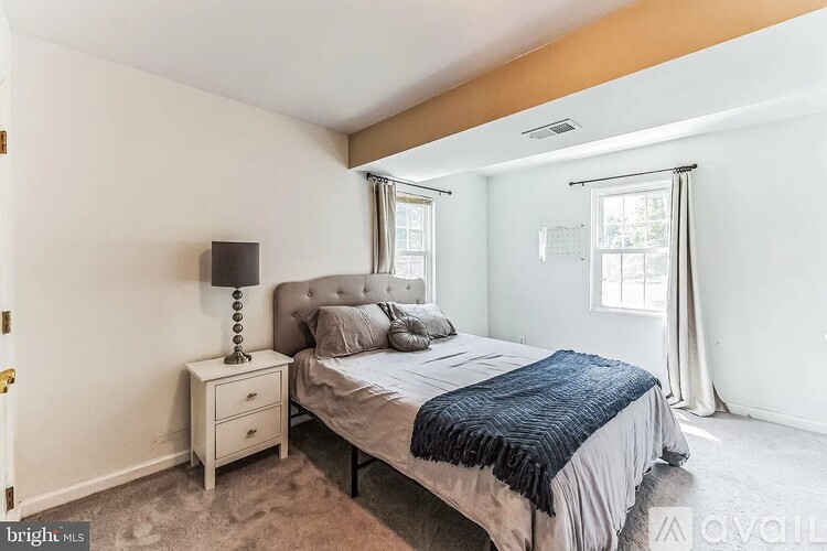 A bedroom with a bed, nightstand, and window.