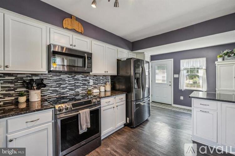 A kitchen with white cabinets and a black refrigerator.