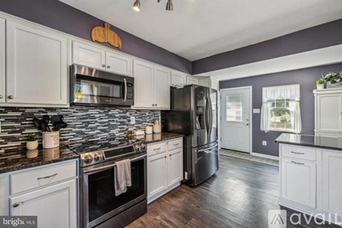 A kitchen with white cabinets and a black refrigerator.