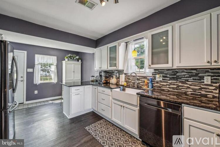 A kitchen with white cabinets and a patterned rug on the floor.