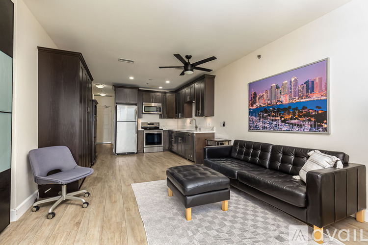 A living room with a black couch and a ceiling fan.