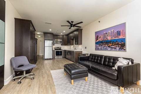 A living room with a black couch and a ceiling fan.
