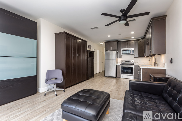 A modern kitchen with a black leather ottoman and a ceiling fan.